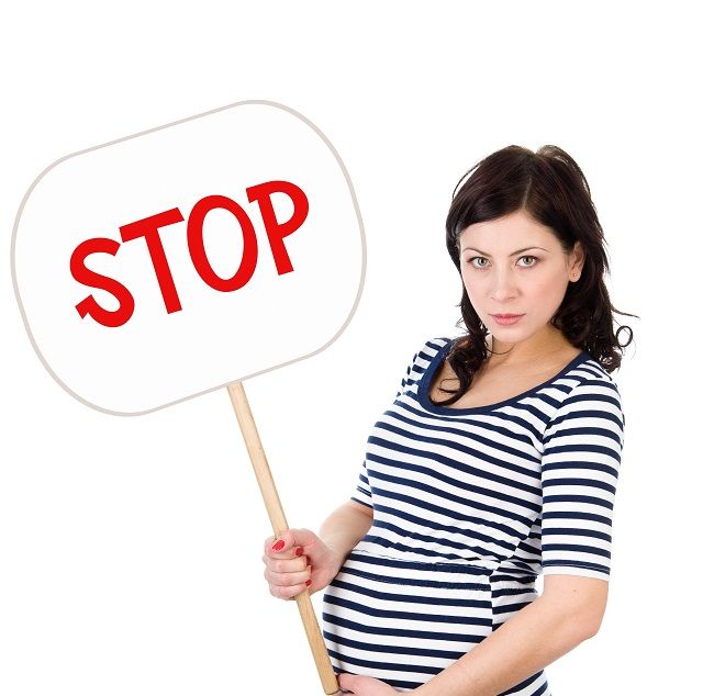 The angry pregnant woman holds the poster with an inscription "Stop"